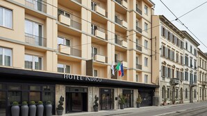 Ett hotell med flera våningar, balkonger, ett svart solskydd och en skylt med texten ”HOTEL INDIGO”.