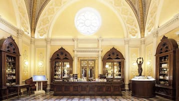 A grand lobby with ornate woodwork, a central reception desk, and a large skylight.