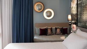A hotel room with a bed, a nightstand, a lamp, and two wall-mounted circular light fixtures. - Hotel Indigo Florence by IHG (Florence)