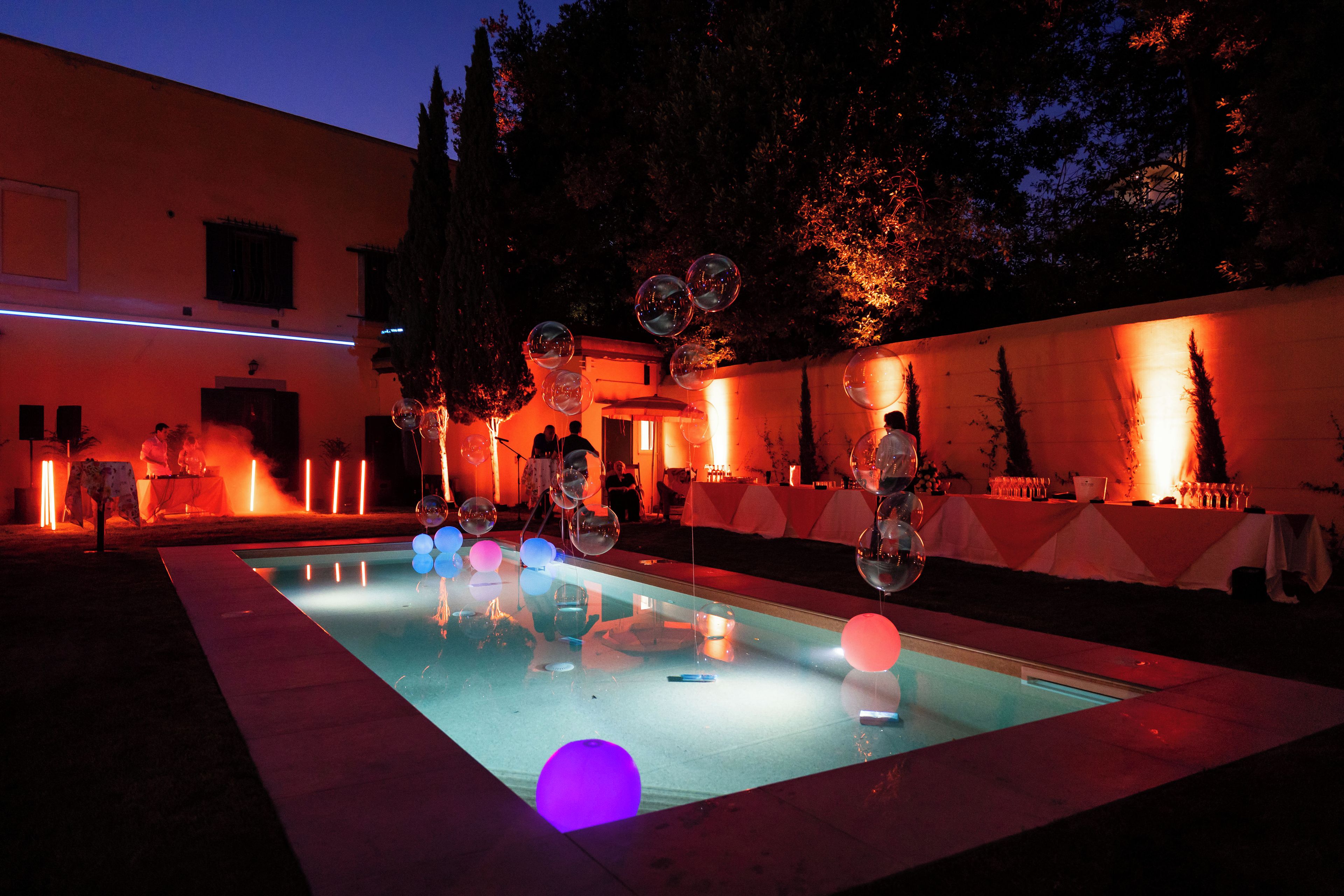 A pool area with a clear water surface, surrounded by a low wall and trees.