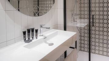 Een moderne badkamer met een wit wastafel, een grote spiegel en een douche.