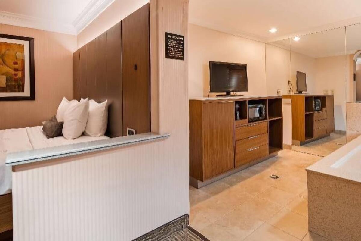 Un baño moderno con bañera, muebles de madera y un televisor.