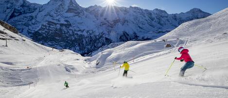 A snowy mountain slope with skiers.