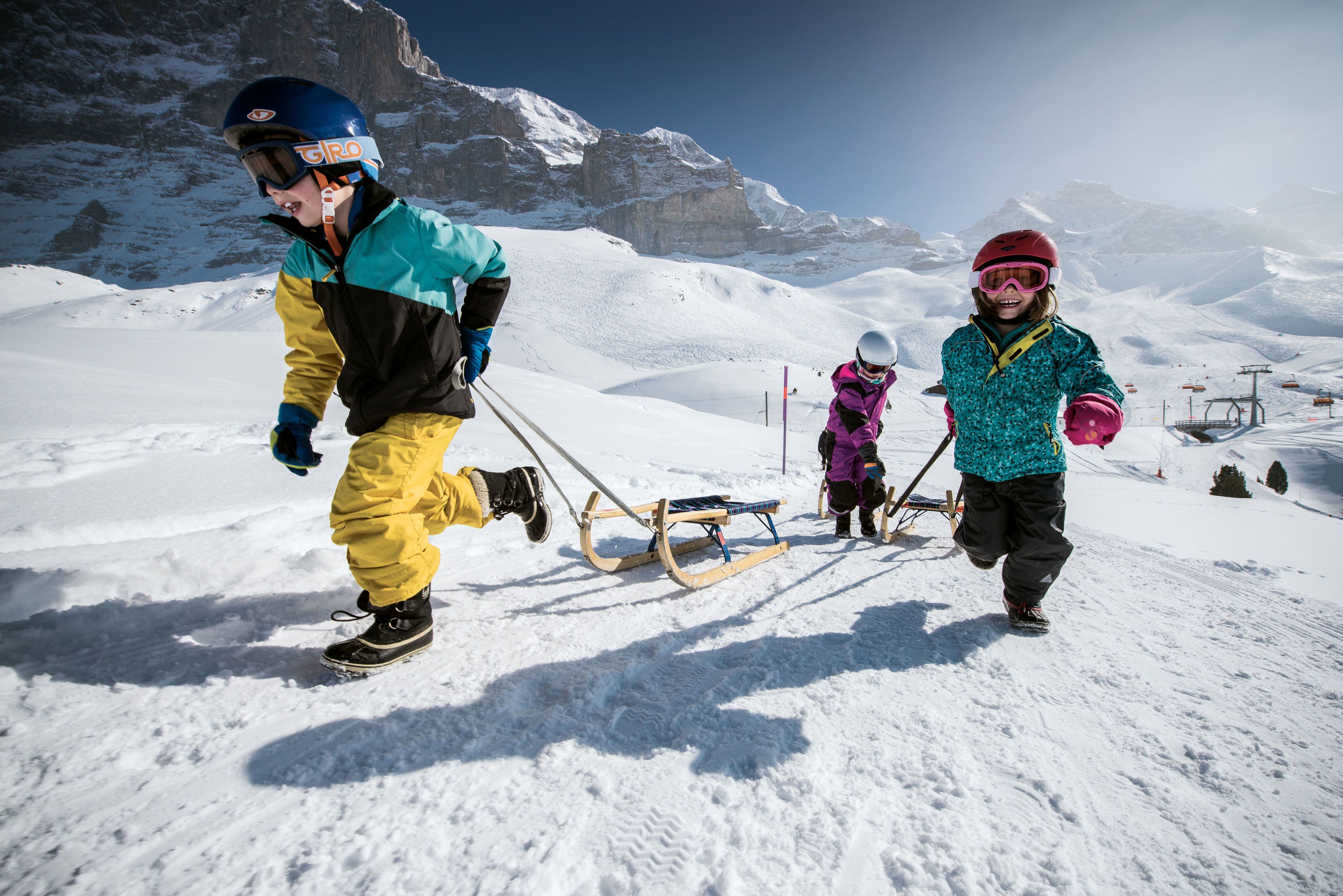 A snowy mountain scene with a sled being pulled by a person.