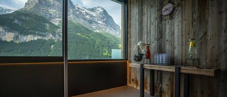 A modern room with a large window overlooking a mountain landscape.