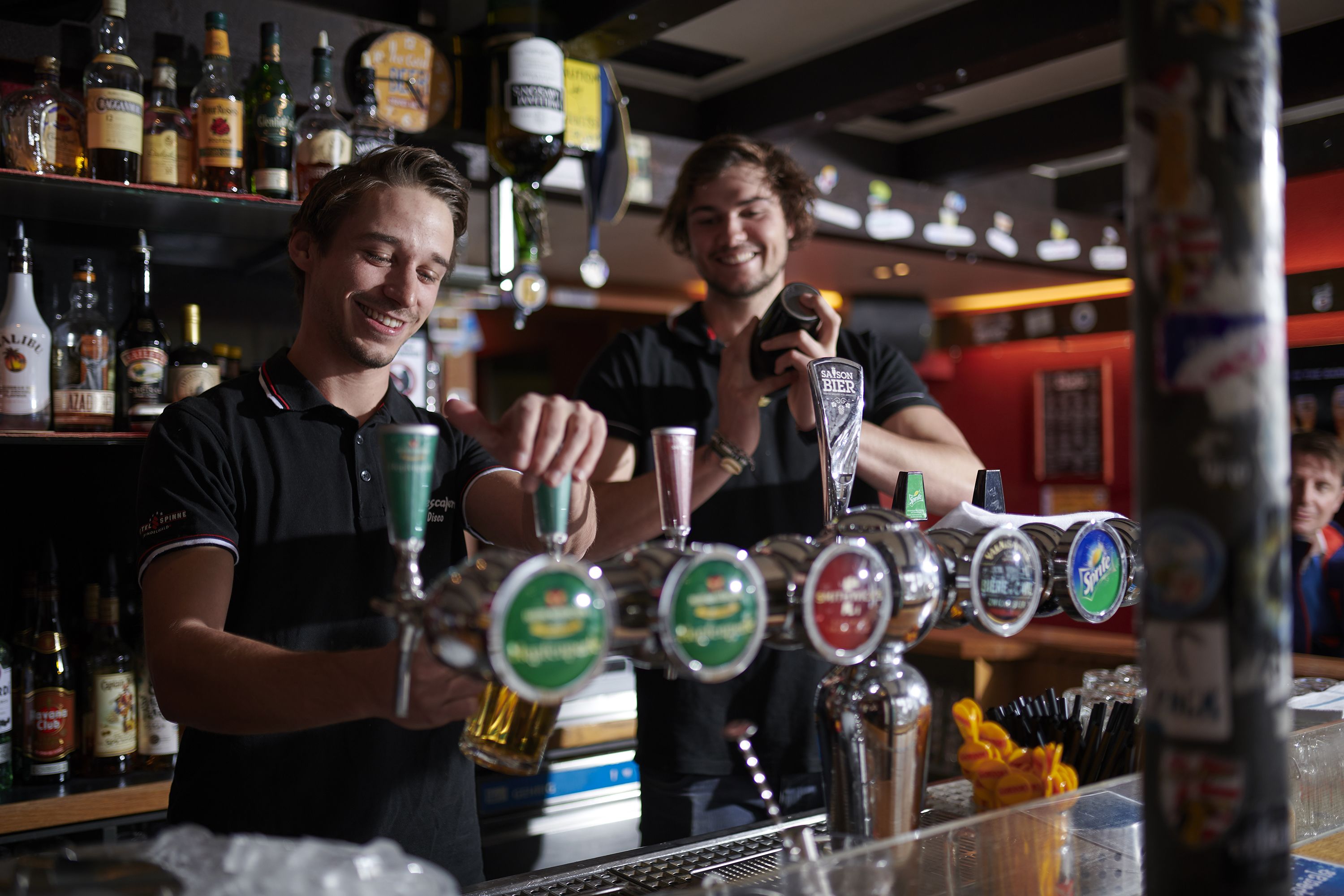 A bar with multiple beer taps and a variety of bottles in the background.