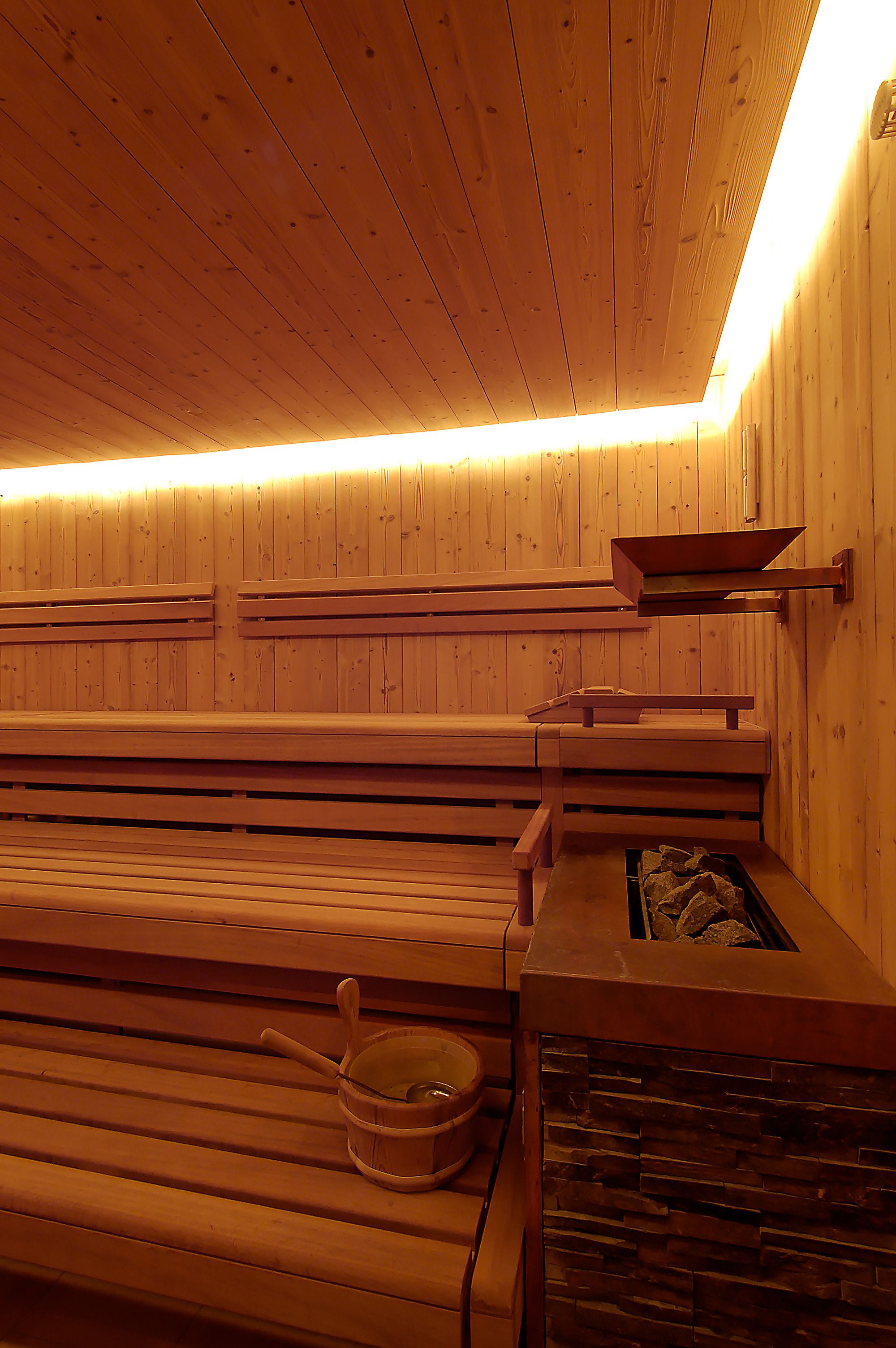 A sauna with wooden benches and a stone basin.