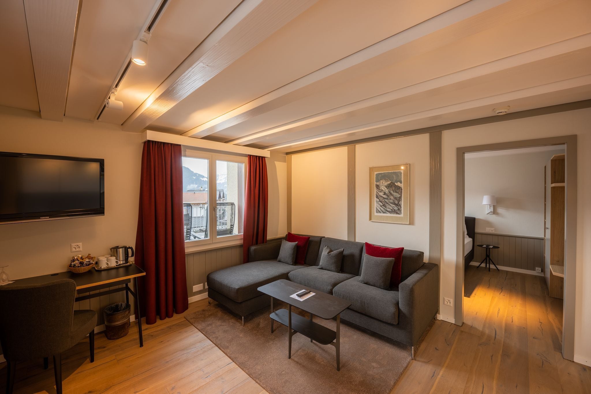 A cozy living room with a sectional sofa, a small table, and a TV.