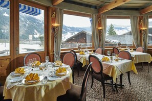 Um restaurante com mesas montadas para refeições, grandes janelas com vista para as montanhas e design de interiores em madeira.