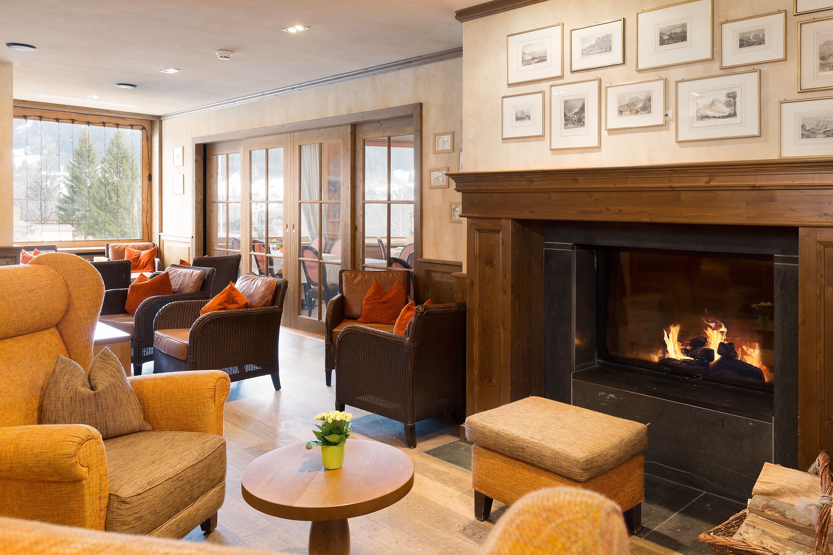 A cozy lounge area with wicker furniture, a fireplace, and framed pictures on the wall.