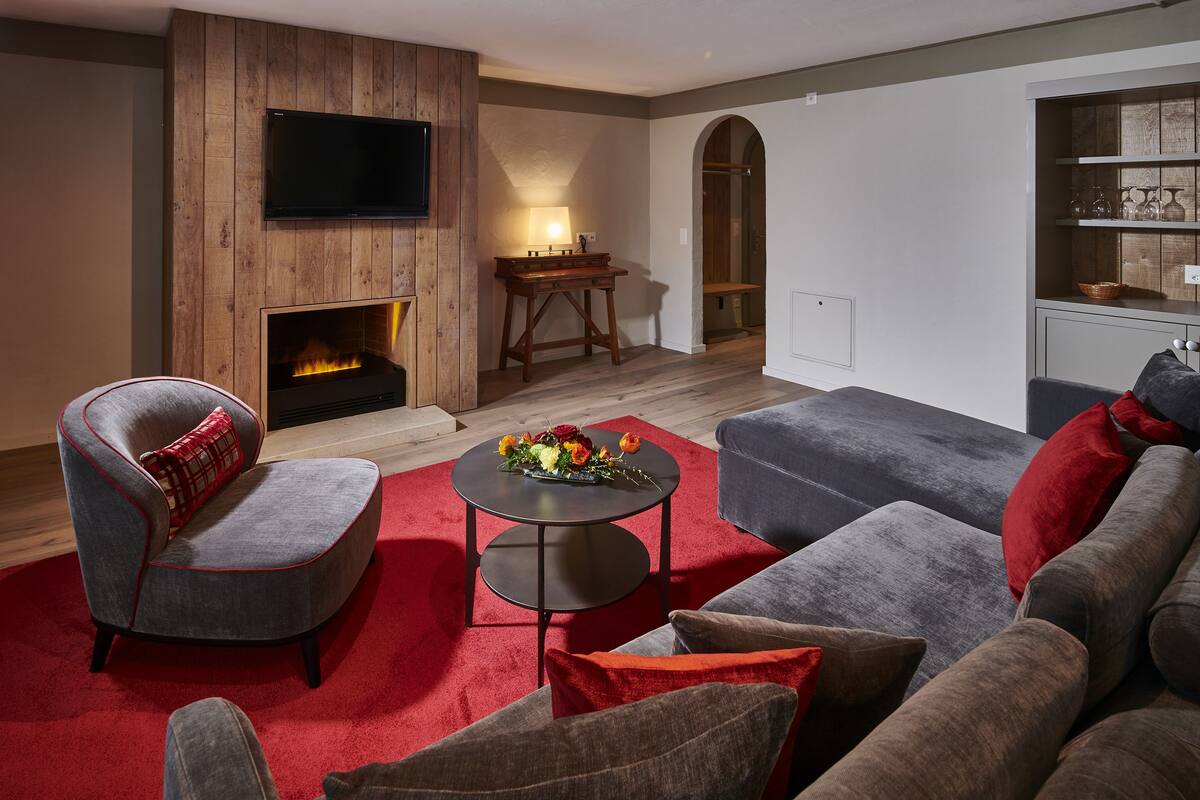 Una sala de estar moderna con chimenea, televisor montado en la pared y una zona de estar acogedora con alfombra roja.