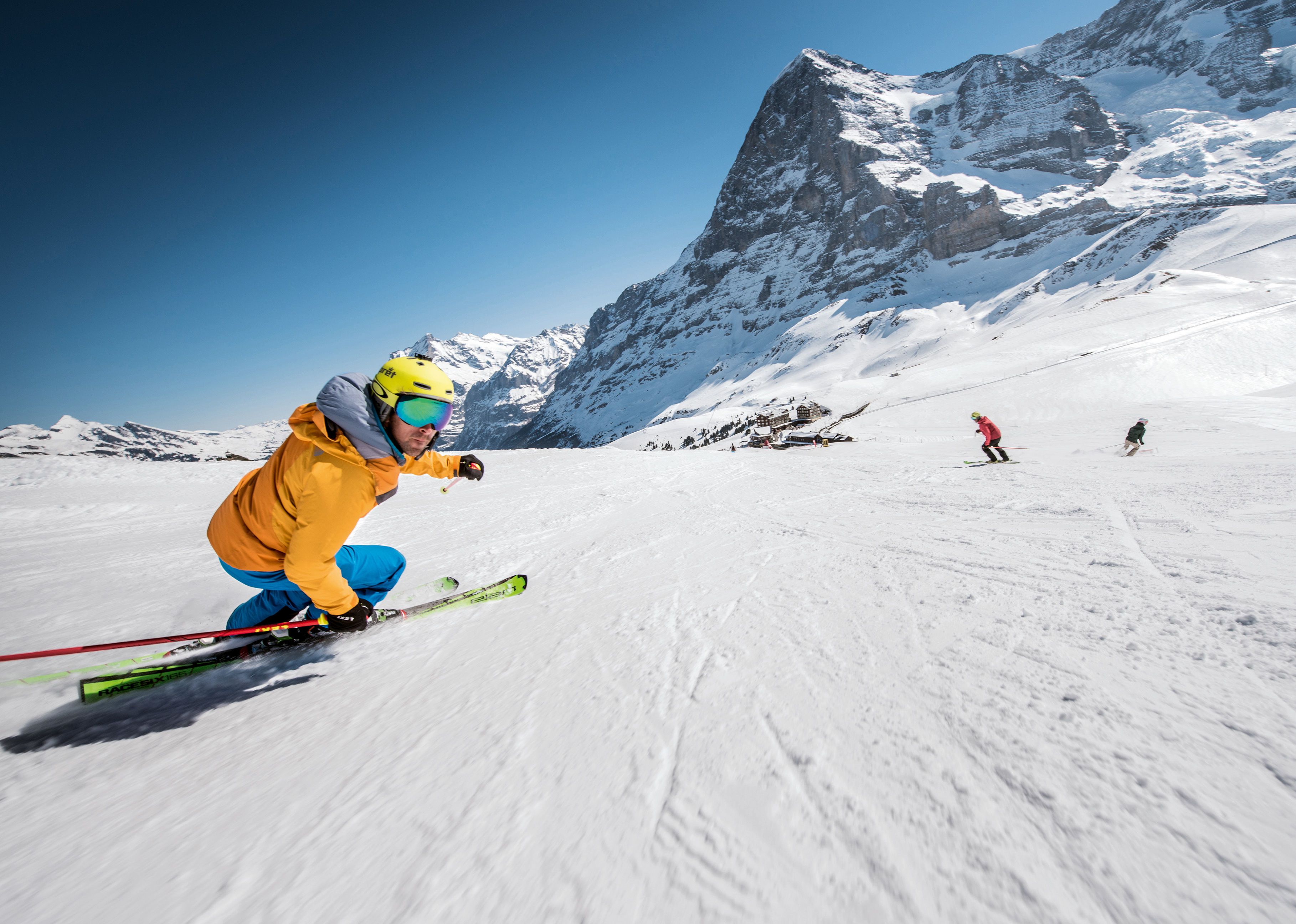 A snowy mountain slope with skiers.