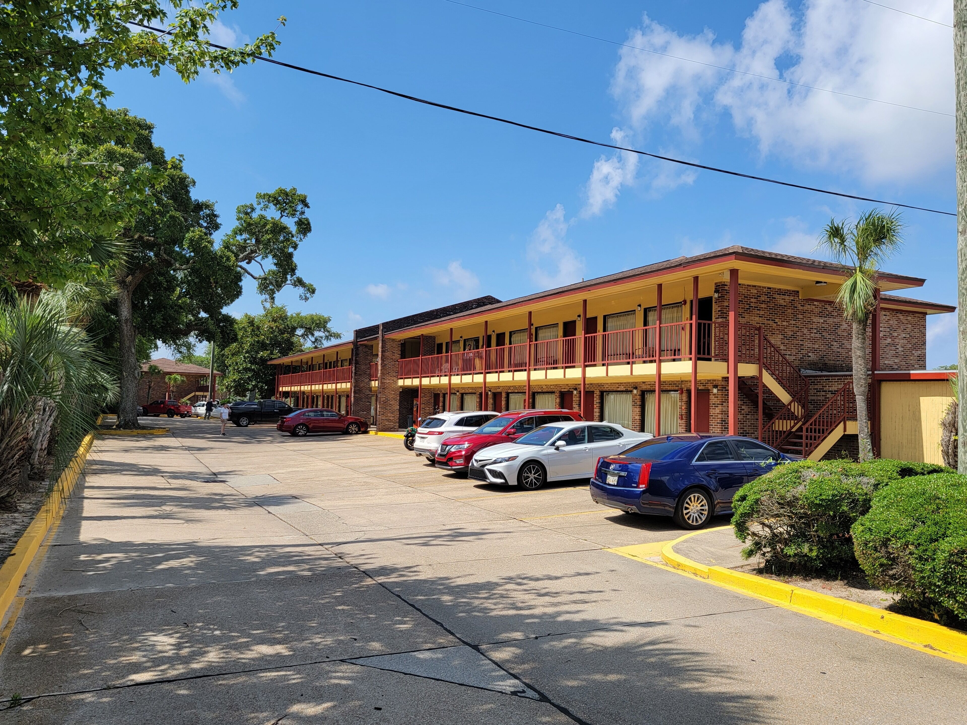 A motel with multiple floors, a parking lot, and a clear blue sky.