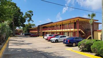 A motel with multiple floors, a parking lot, and a clear blue sky.