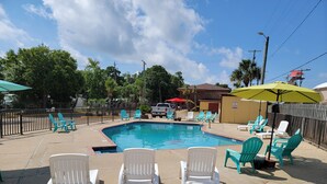 A swimming pool with chairs and umbrellas, surrounded by a fence and trees. - Twin Star Lodge (Biloxi)