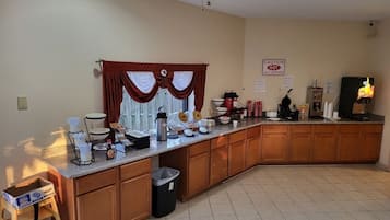 Una cocina con una barra larga, armarios de madera, un cubo de basura y un ventilador de techo.