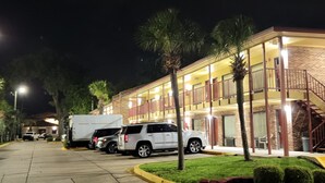 A multi-story hotel with a brick facade, multiple balconies, and a parking area with several vehicles. - Twin Star Lodge (Biloxi)