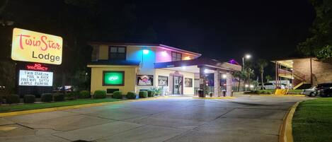 A Twin Star Lodge with a neon sign, a pool, and ample parking.