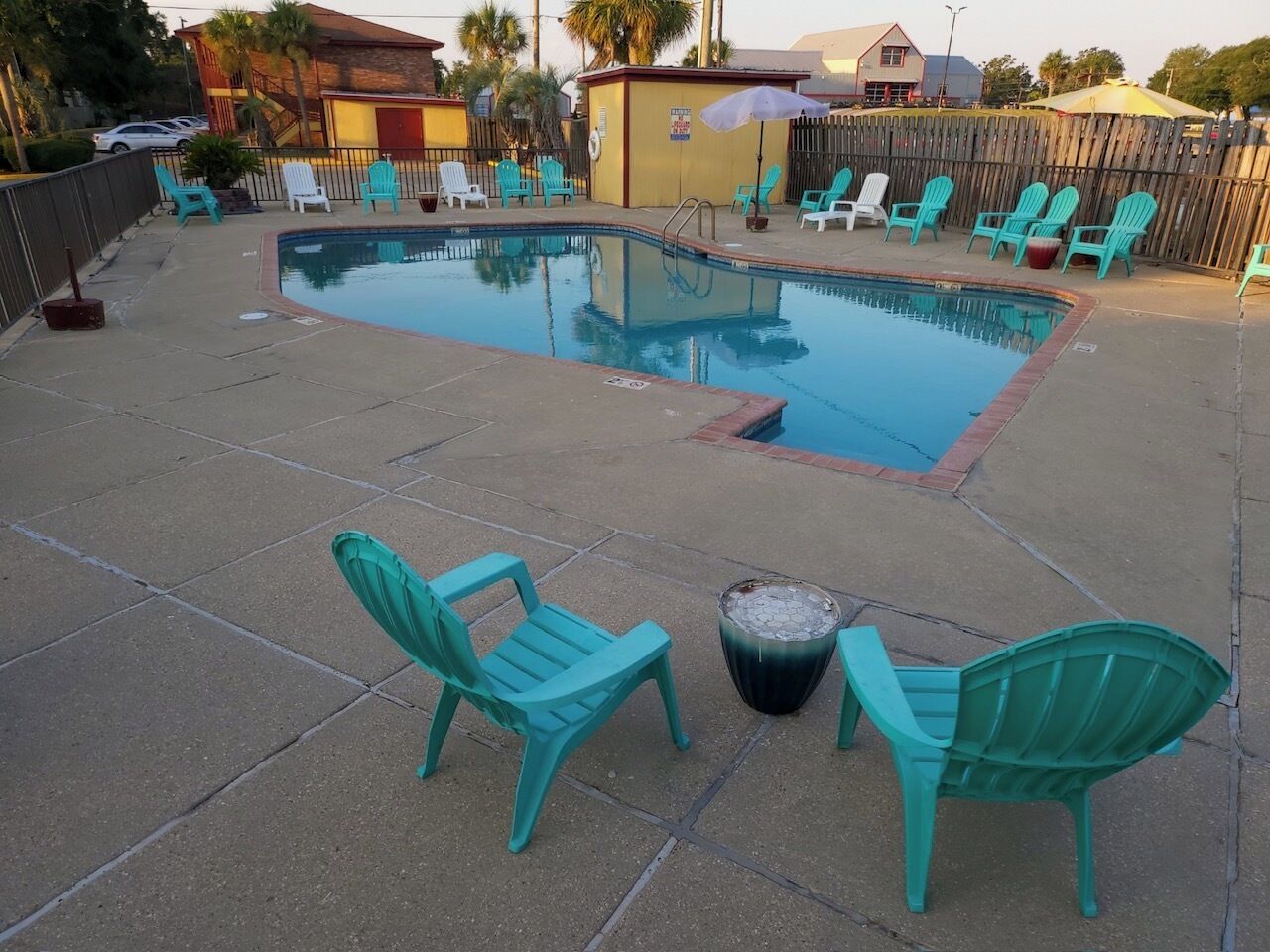 A swimming pool with turquoise chairs and a fire pit.