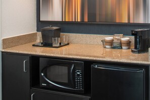 Una cocina con microondas, cafetera y dispensador de café.