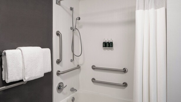A bathroom with a bathtub, handrails, a towel rack, and a shower control panel. - Courtyard by Marriott Dulles Airport Herndon/Reston (Herndon)