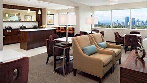 A modern hotel room with a city view, a dining area, and a kitchen. - Sheraton Cavalier Calgary Hotel (Calgary)