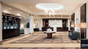 A modern lobby with a central round table, seating areas, and a reception desk. - Sheraton Cavalier Calgary Hotel (Calgary)