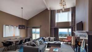 A modern living room with a large sofa, a dining table, and a fireplace. - Hotel Hermosa (Hermosa Beach)