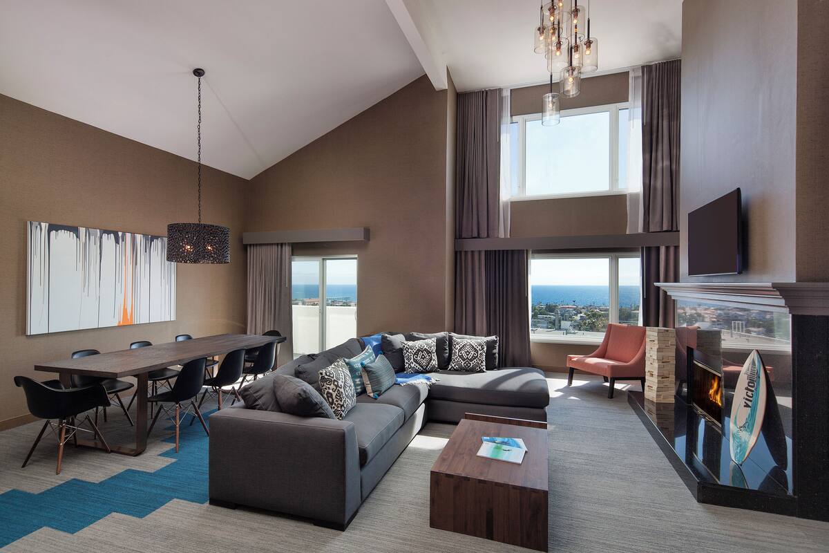 A modern living room with a large sofa, a dining table, and a fireplace.