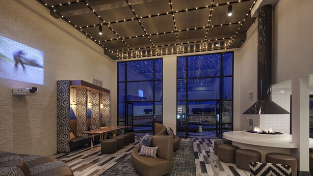 A modern lounge area with a fireplace, comfortable seating, and a large screen displaying a video. - Hotel Hermosa (Hermosa Beach)
