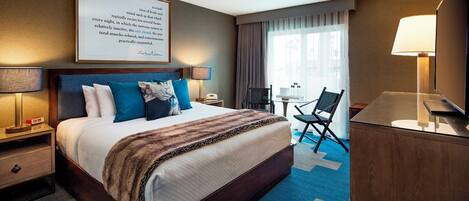 Une chambre d’hôtel avec un grand lit, un bureau, une chaise et un téléviseur.