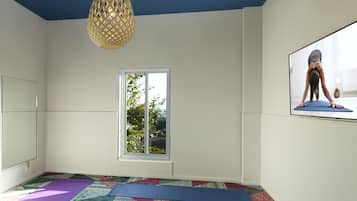 A yoga room with mats, a patterned carpet, a decorative ceiling, and a hanging light fixture.