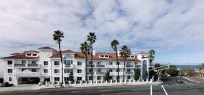 A multi-story hotel with a white facade and red-tiled roof, featuring balconies and palm trees. - Hotel Hermosa (Hermosa Beach)