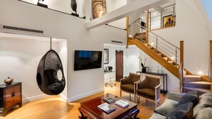 A spacious living area with a hanging chair, a staircase, and a flat-screen TV. - The May Fair Hotel, Mayfair, London (London)