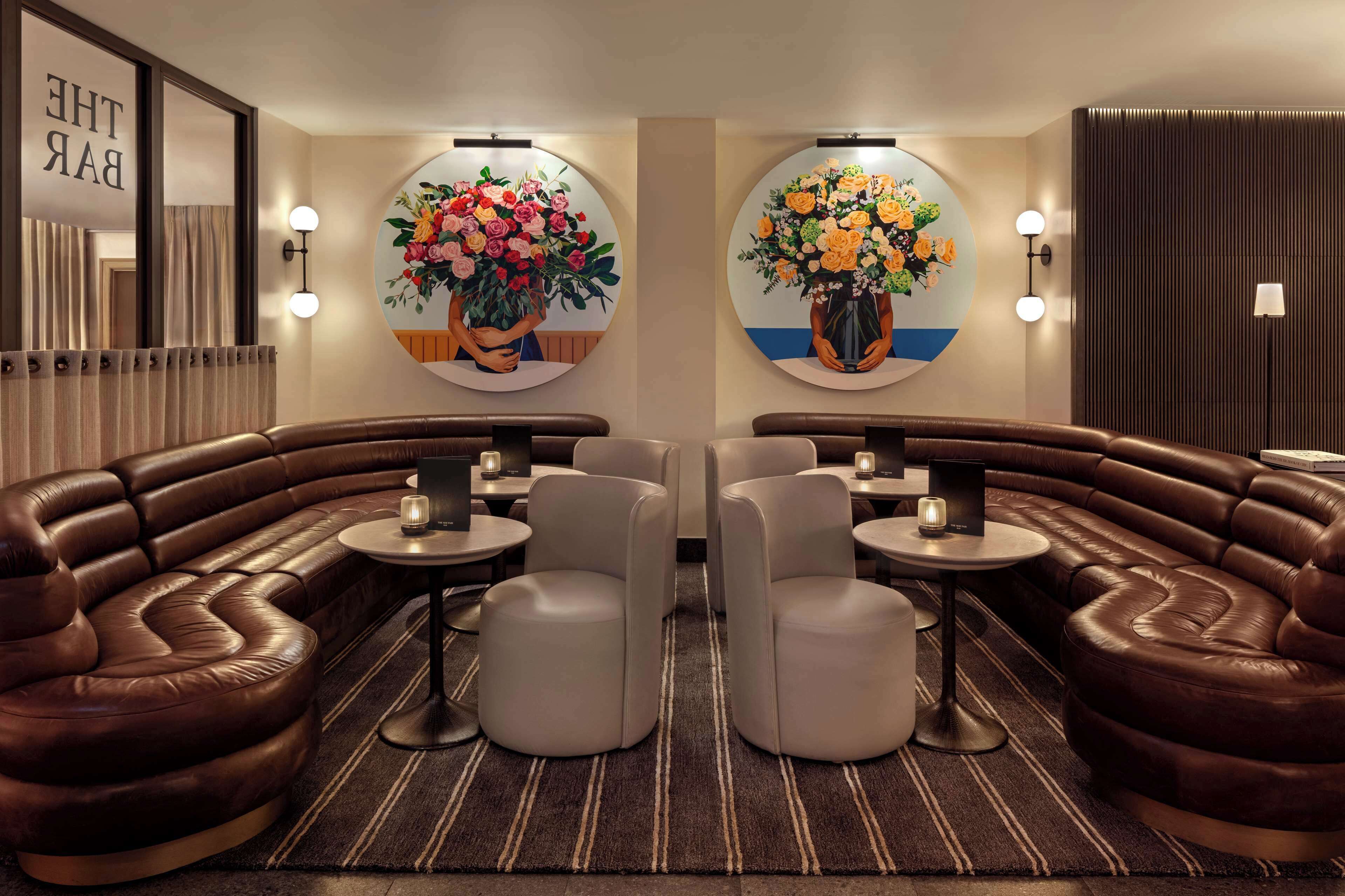 A modern lounge area with leather sofas, round tables, and wall-mounted light fixtures.