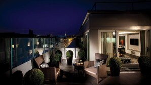 A rooftop terrace with seating, potted plants, and a view of the cityscape at night. - The May Fair Hotel, Mayfair, London (London)