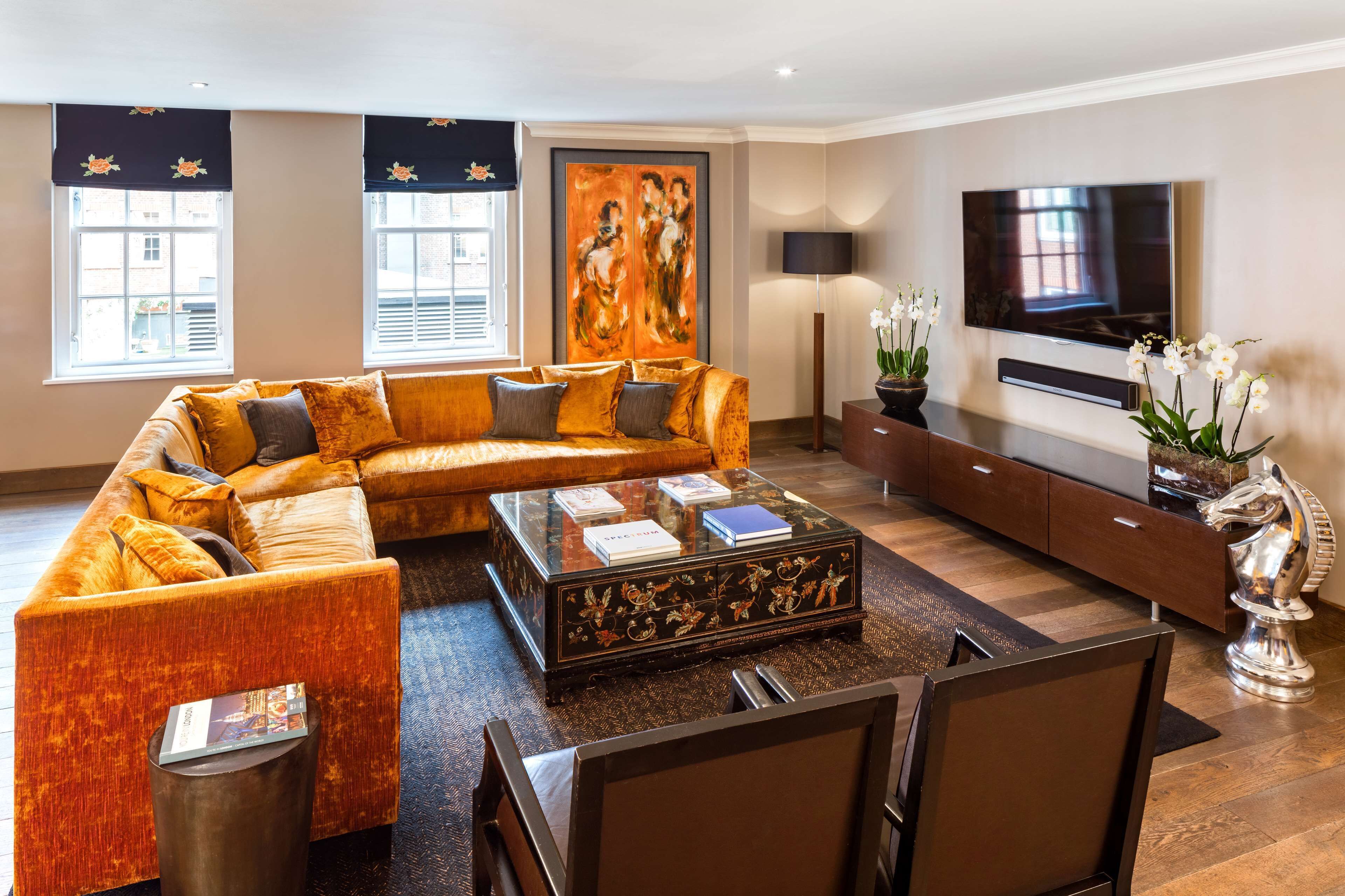 A modern living room with a sectional sofa, a glass coffee table, a flat-screen TV, and a decorative plant.