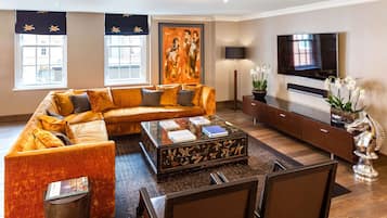 A modern living room with a sectional sofa, a glass coffee table, a flat-screen TV, and a decorative plant.