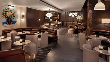Un espace de détente moderne avec des canapés en cuir, des tables rondes et un éclairage d’ambiance.