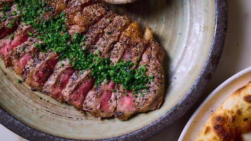 A steak with green garnish on a ceramic plate.