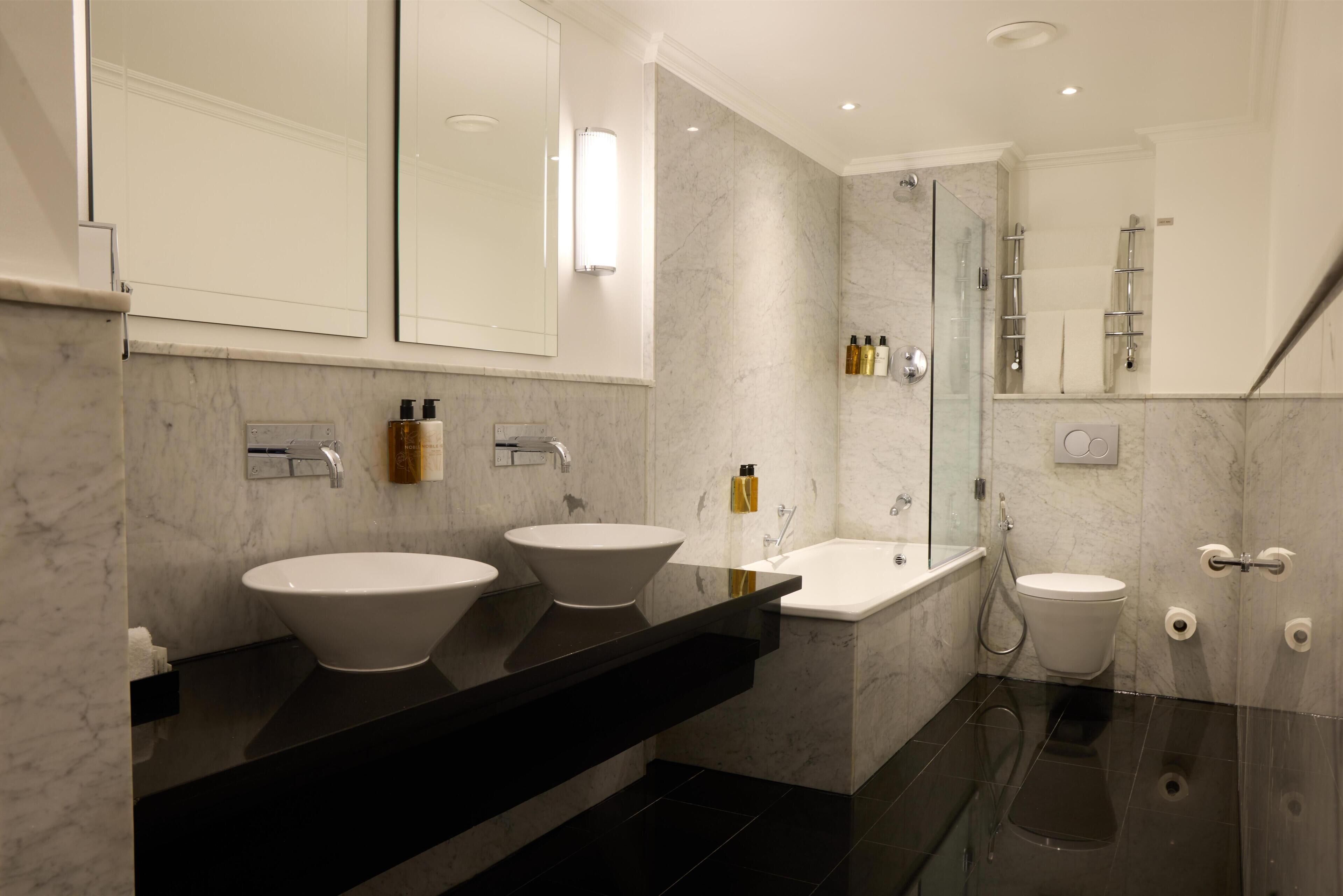 Un baño moderno con dos lavabos, una bañera y una ducha.