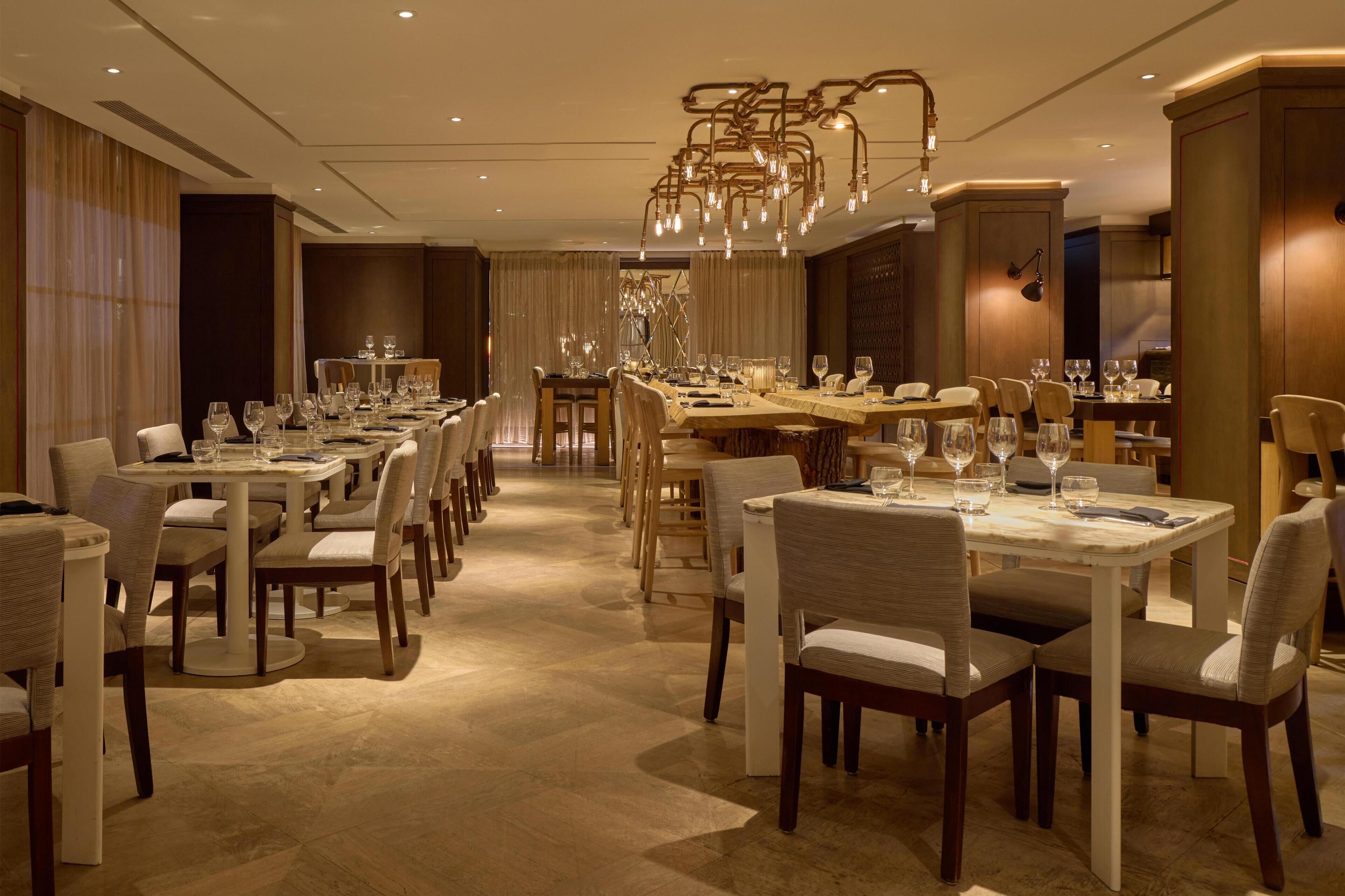 A spacious dining area with multiple tables and chairs, elegant chandeliers, and a warm, inviting atmosphere.