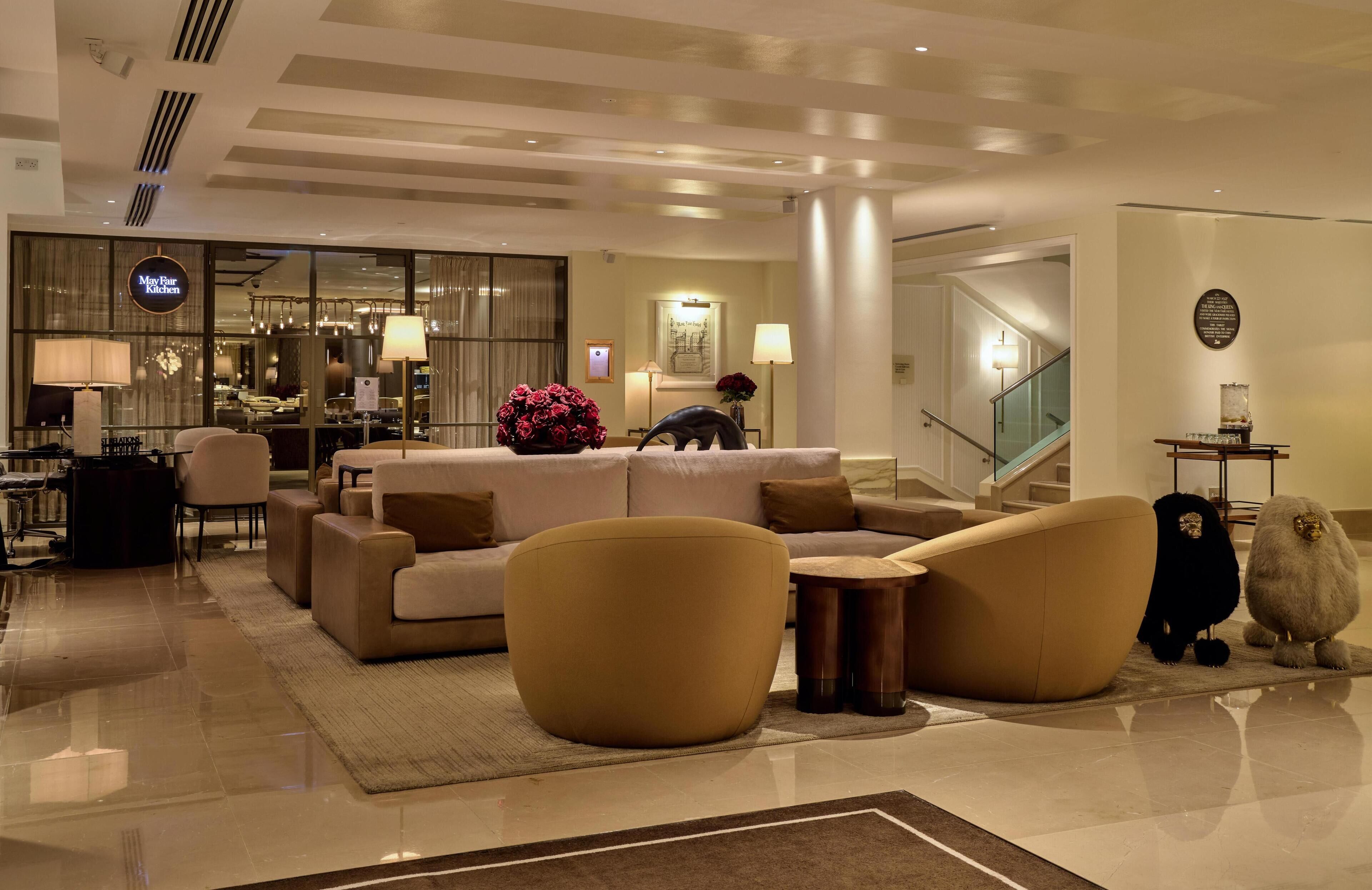 Un lobby moderno de hotel con un área de descanso, una recepción y vistas al área de la cocina.