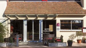 A hotel entrance with a red 'ibis' sign, a glass door, and outdoor seating. - ibis Chatellerault (Chatellerault)