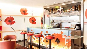 A bar area with stools, a counter with beverages, and a dartboard. - ibis Chatellerault (Chatellerault)