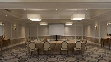 A conference room with a large table, chairs, a projector screen, and a carpeted floor.