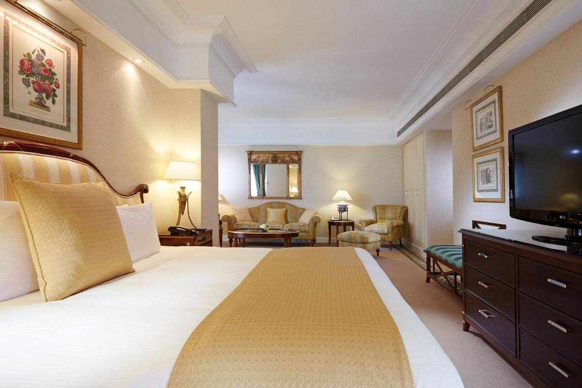 Een hotelkamer met een groot bed, een televisie, een bureau en een stoel.