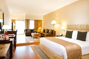 Una habitación de hotel con una cama grande, un sofá, un escritorio y una televisión.