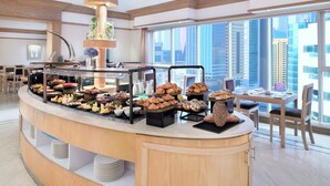 Een buffet met verschillende soorten eten, een koffiehoek en een zithoek met uitzicht over de stad.