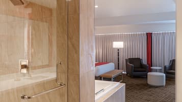 A modern bathroom with a shower, a toilet, and a sink. The room has a large mirror, a towel rack, and a glass shower enclosure. The bathroom features a marble floor and a glass shower door.